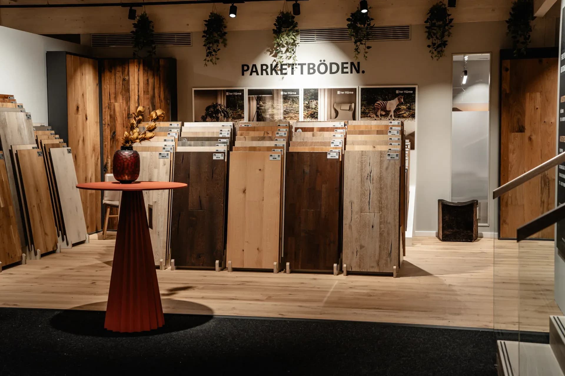 Parkett-Abteilung der Frey-Ausstellung in Kandel: Musterdielen in Eiche und dunklen Hölzern auf Ständern, davor ein roter Stehtisch