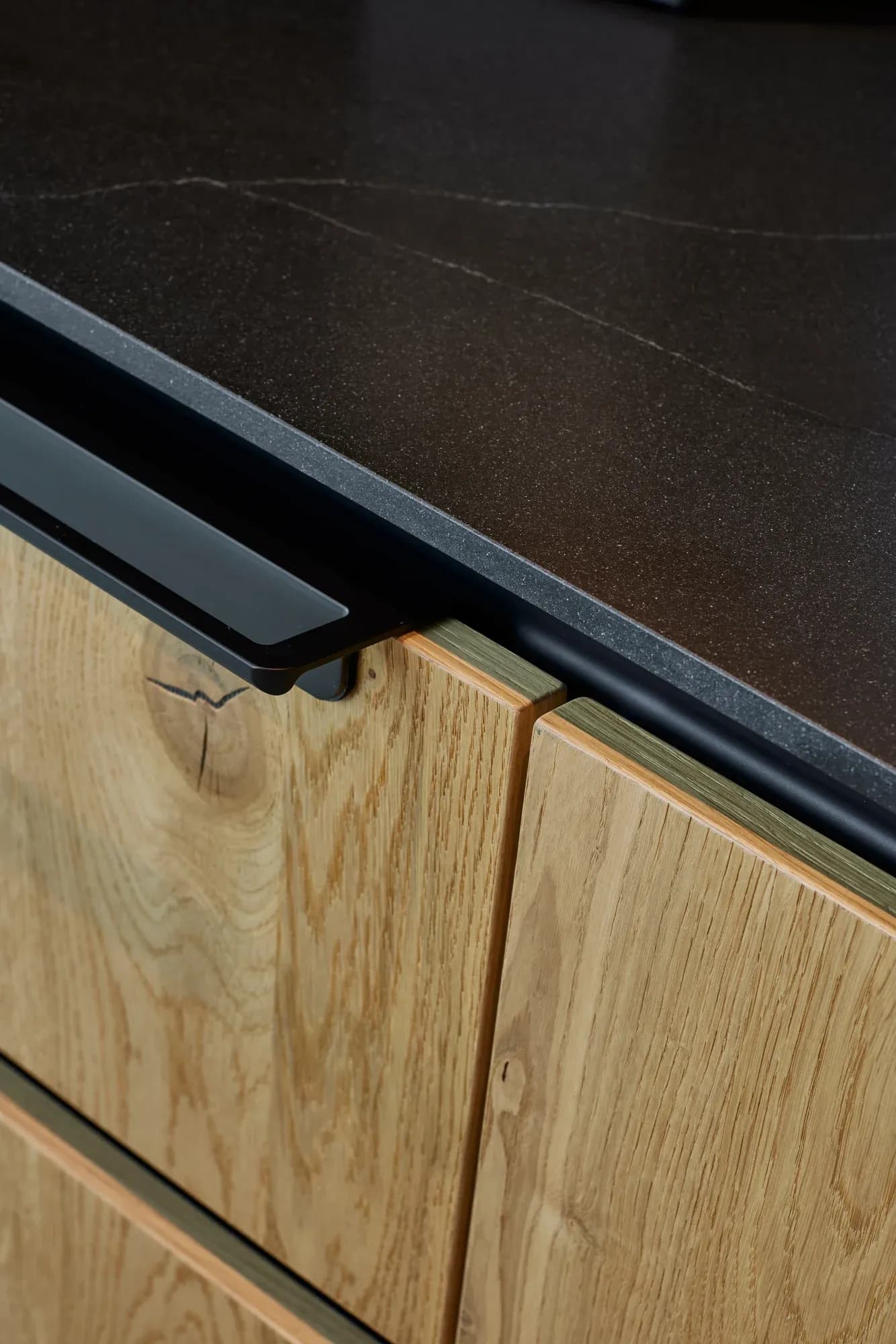 Detail: Eiche-Front und schwarze Natursteinkante mit eingelassenem Griff