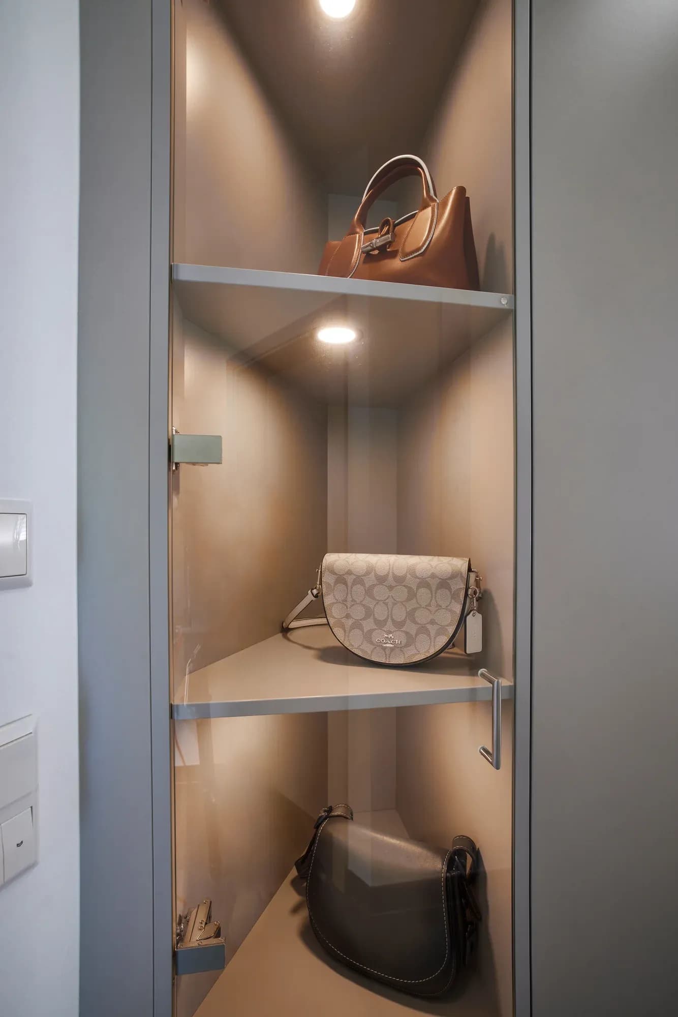 Beleuchtete Vitrinennische mit Glasböden und integriertem LED-Spot, innen mit hellem Holz ausgekleidet.