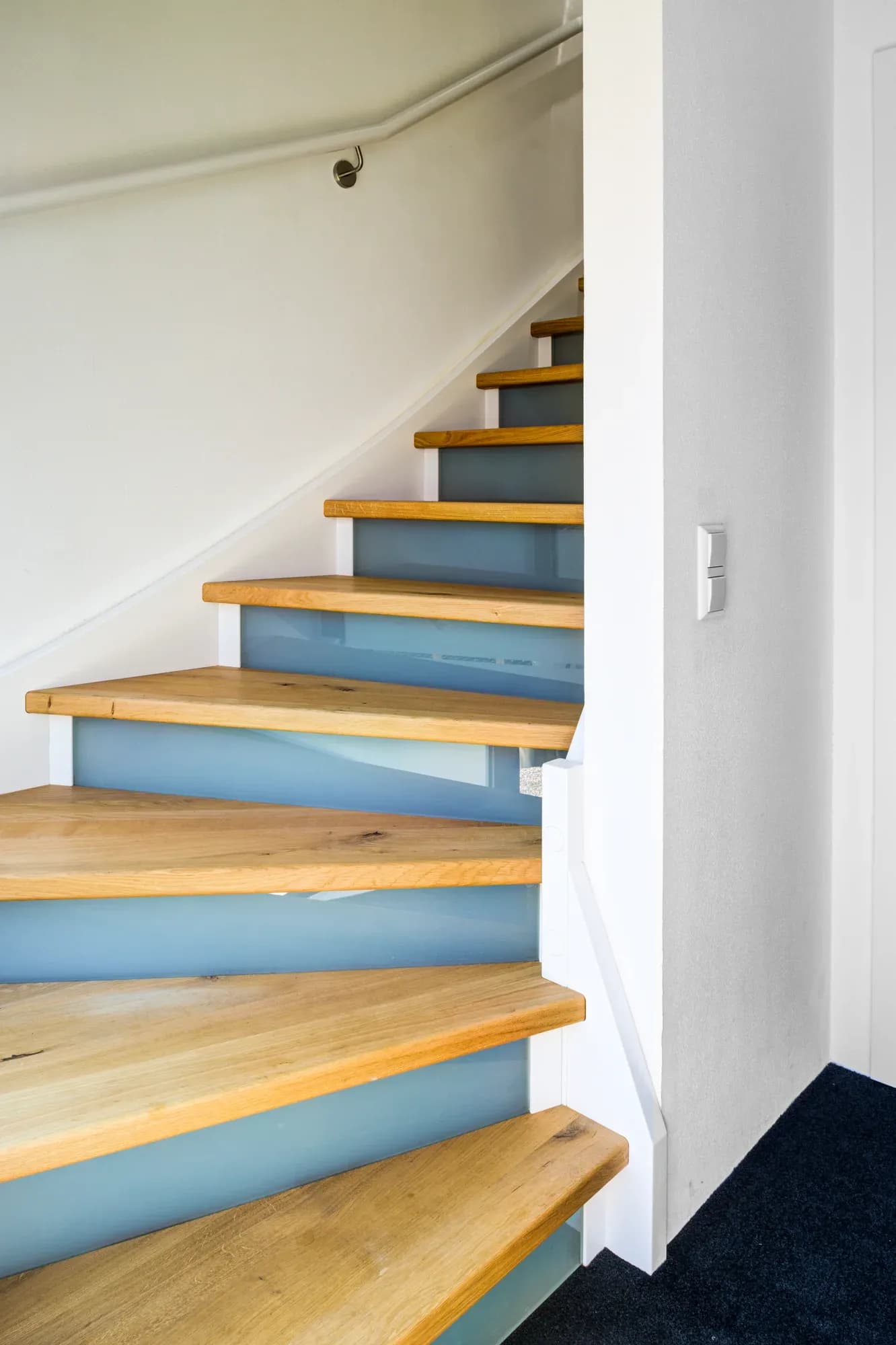 Massivholztreppe mit Eichenstufen und satiniert leuchtenden Glas-Setzstufen an weiß lackierter Wange