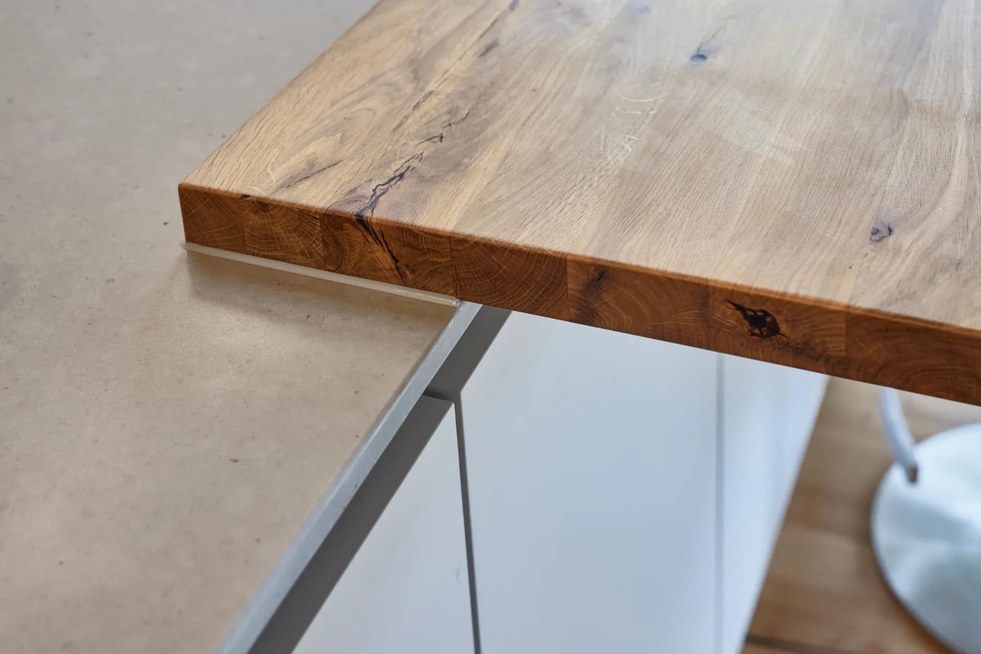 Detail des massiven Eichentresens mit naturbelassener Kante über einer grifflosen Front.
