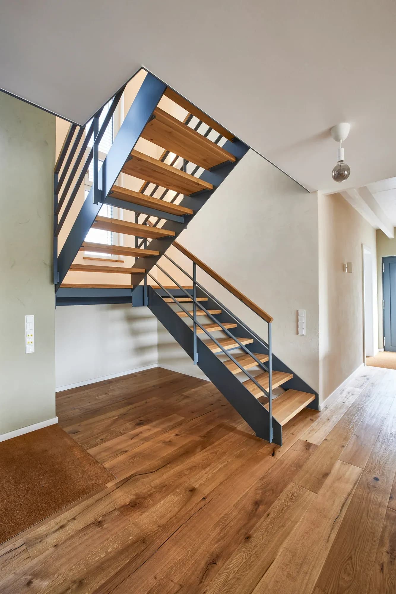 Stahl-Eiche-Treppe im offenen Wohnraum mit durchgehendem Eichendielenboden.
