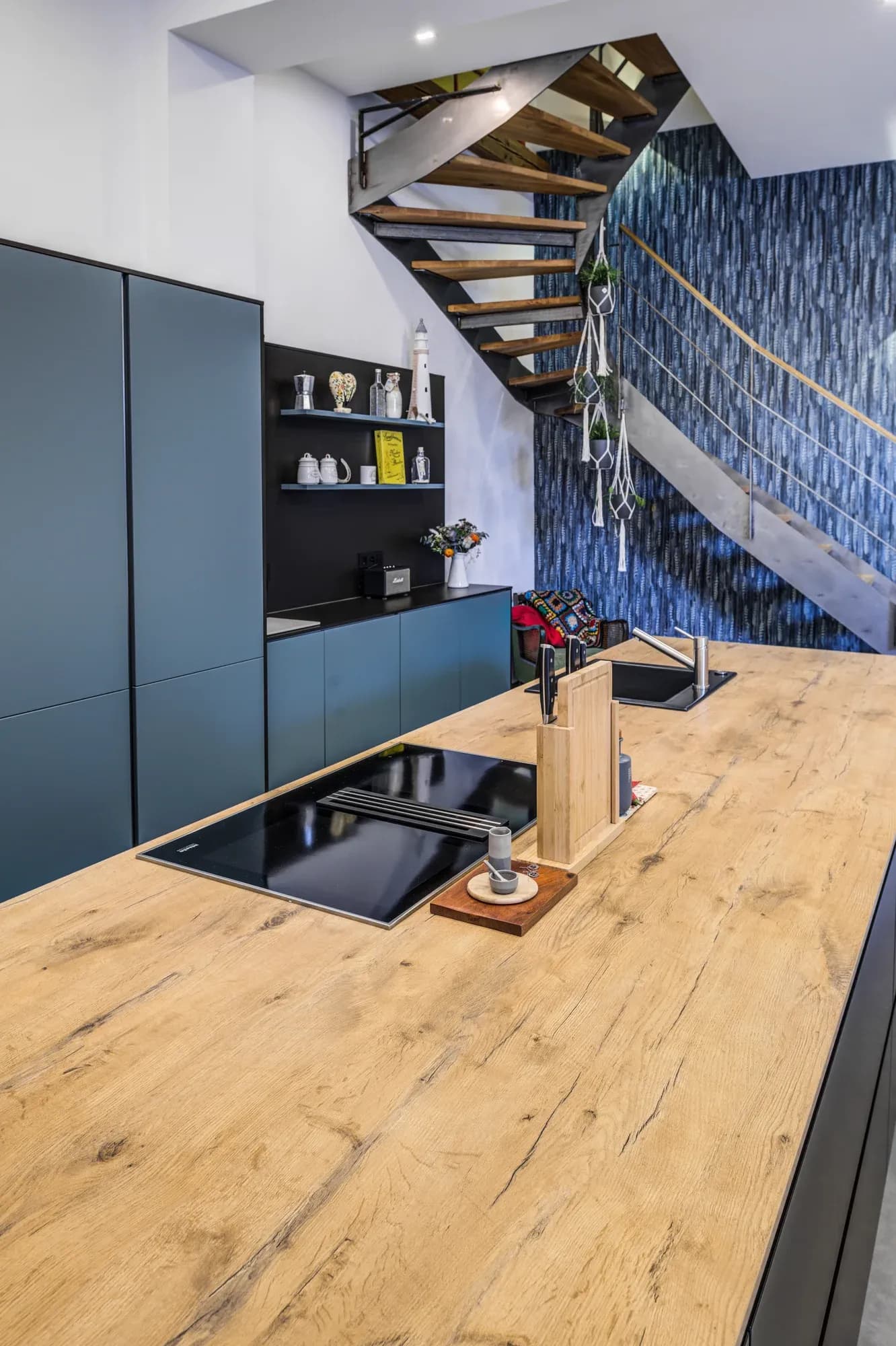 Blick über die Eiche-Arbeitsplatte mit eingelassenem Kochfeld, dahinter die Stahltreppe.