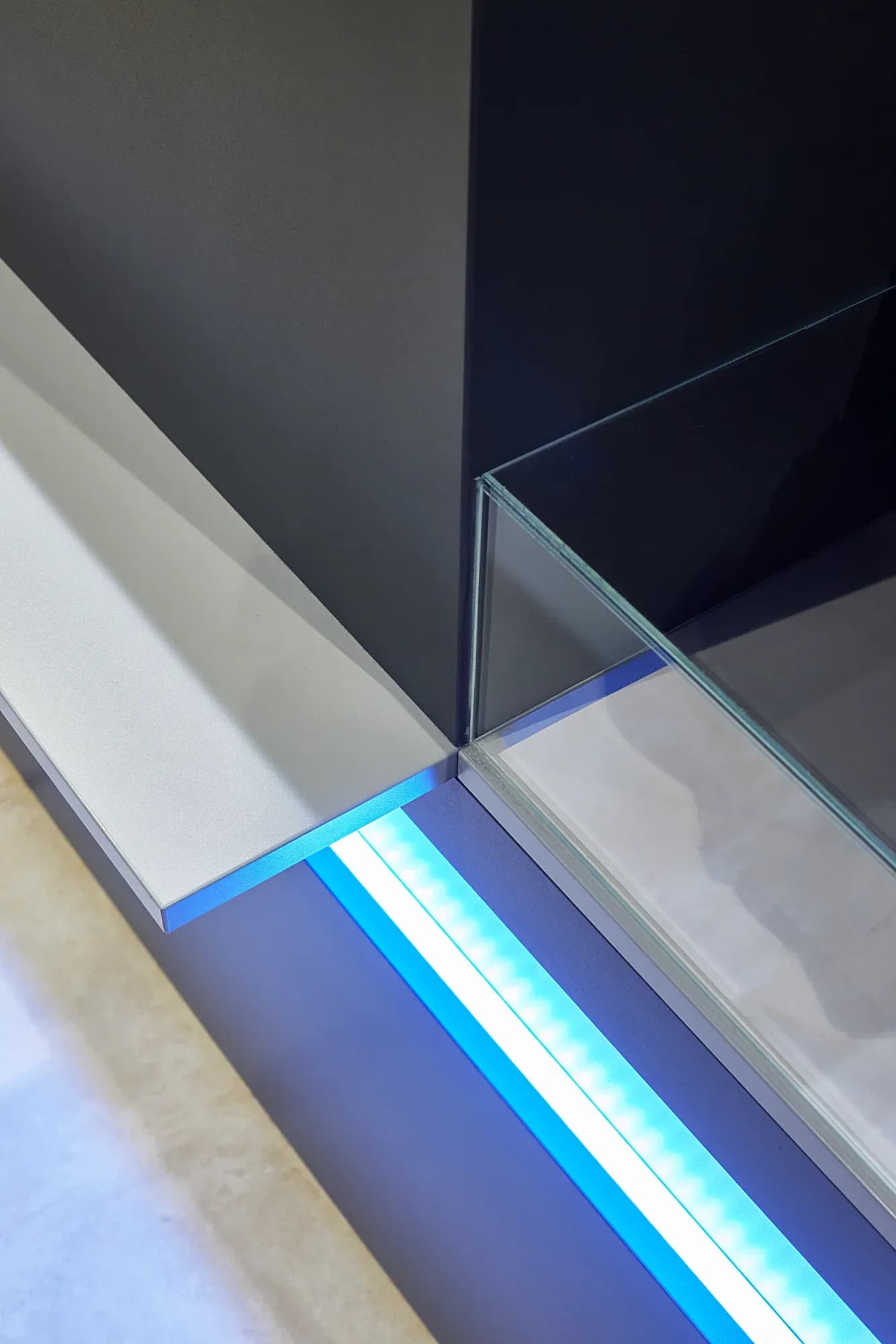 Nahaufnahme der Tresenecke: LED-Lichtband zwischen Glaskante und heller Arbeitsfläche.
