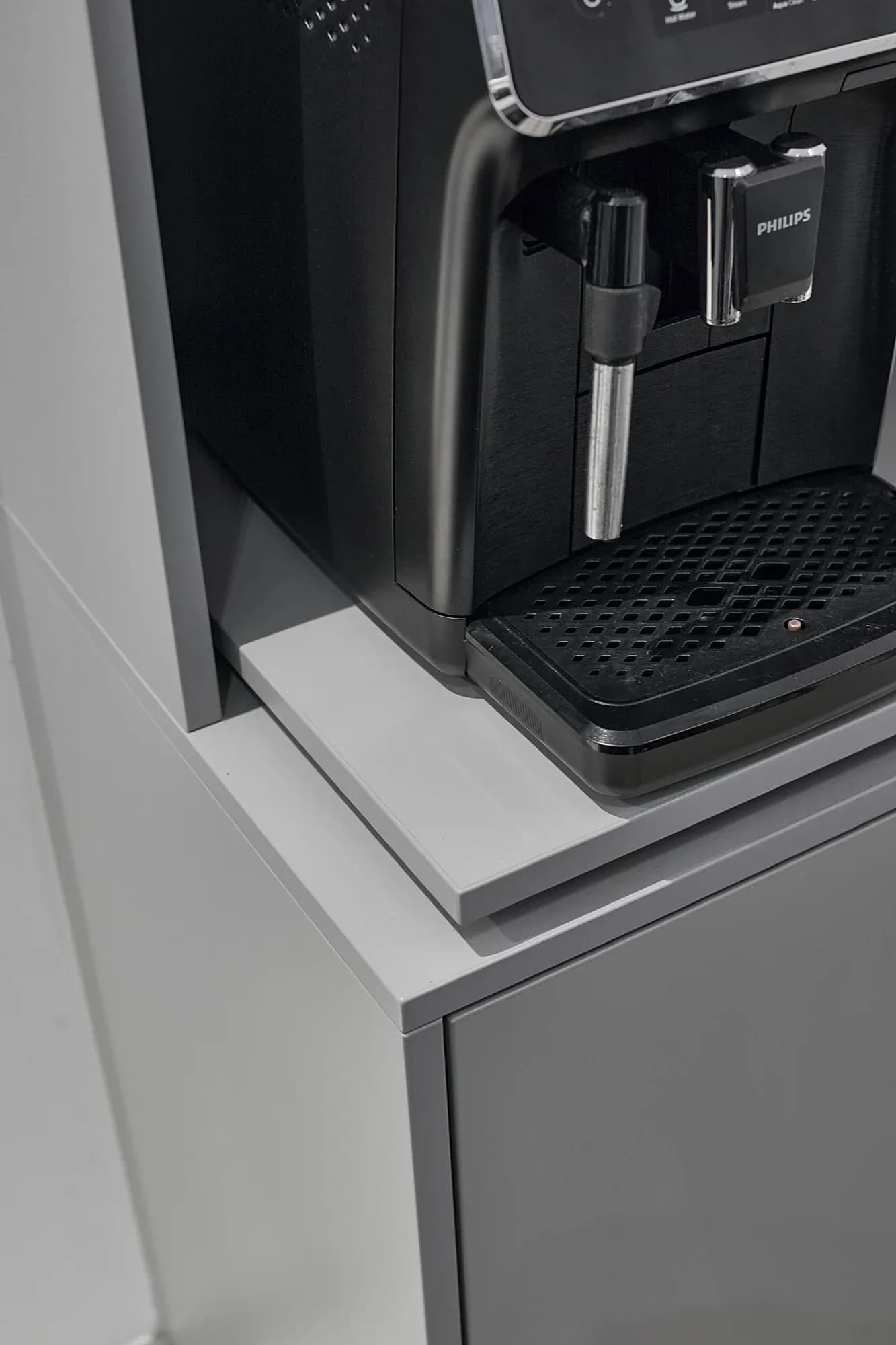 Kaffeemaschine auf einer ausziehbaren hellen Ablage im Tresen.