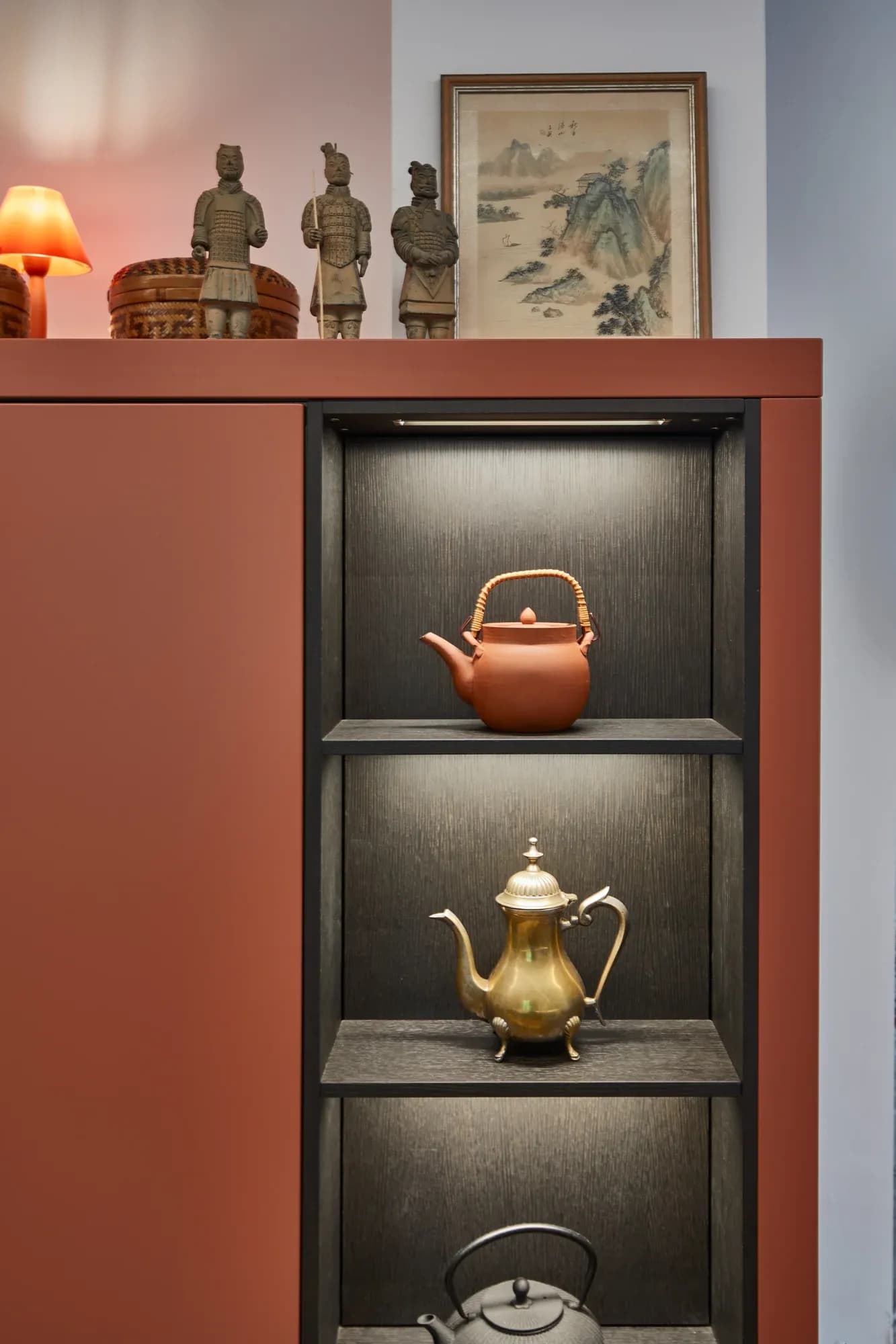 Nahaufnahme der Miele-Einbaugeräte: zwei Backöfen und ein Weinklimaschrank hinter Glas in terrakottafarbenen Fronten, oben Kupfertöpfe.