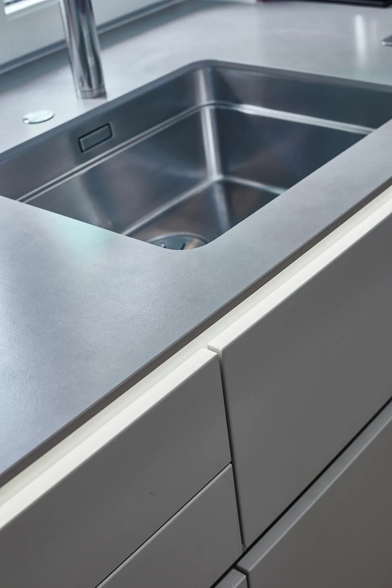 Flächenbündig eingelassene Edelstahlspüle von Blanco in einer grauen Arbeitsfläche.