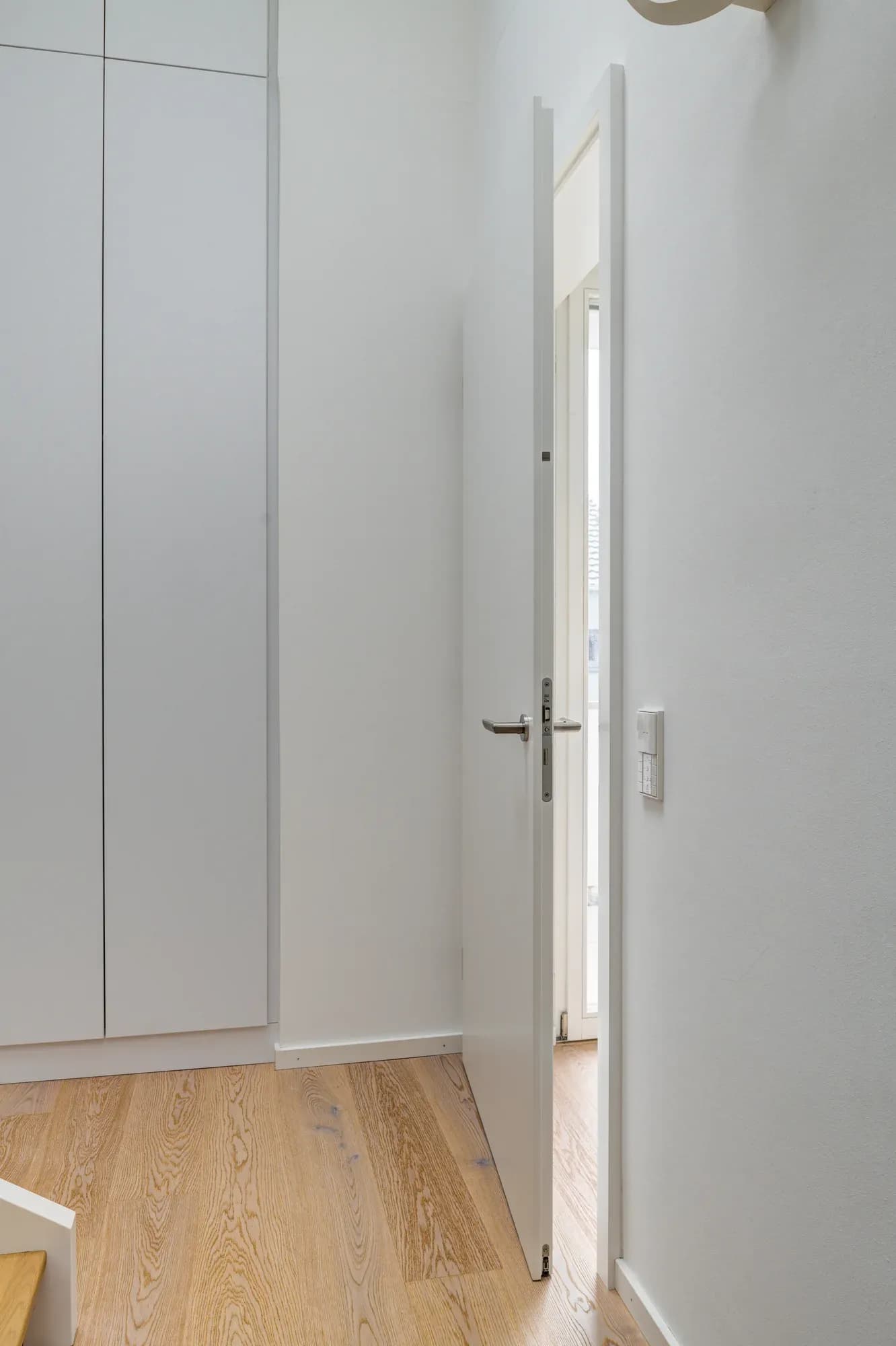 Heller Flur mit weißem Einbauschrank und raumhoher Tür