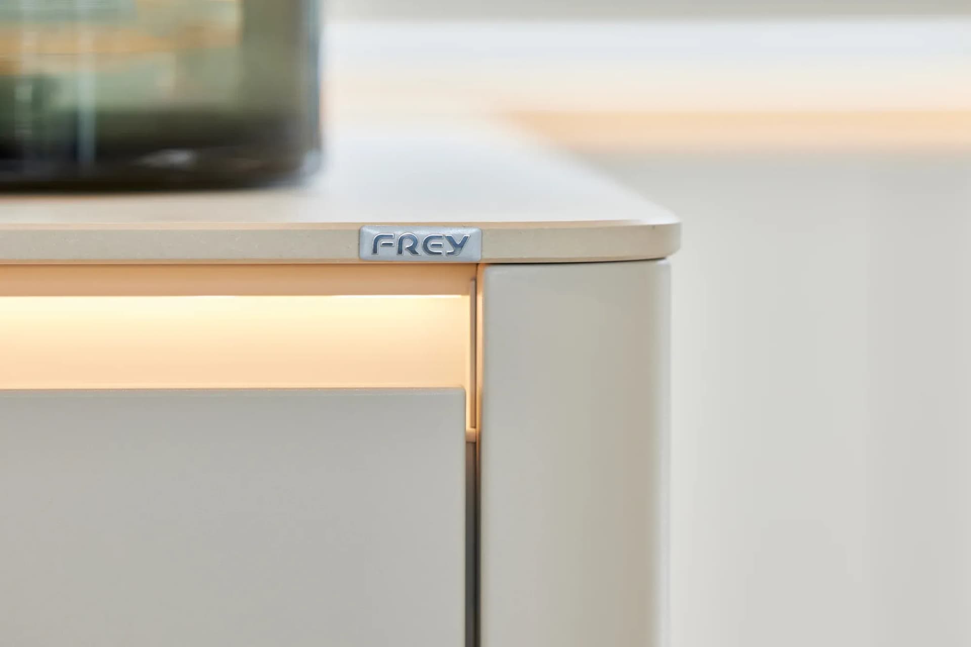 Gerundete Kante der Natursteinplatte mit indirekter Lichtfuge und kleinem Frey-Schild an der Unterseite.