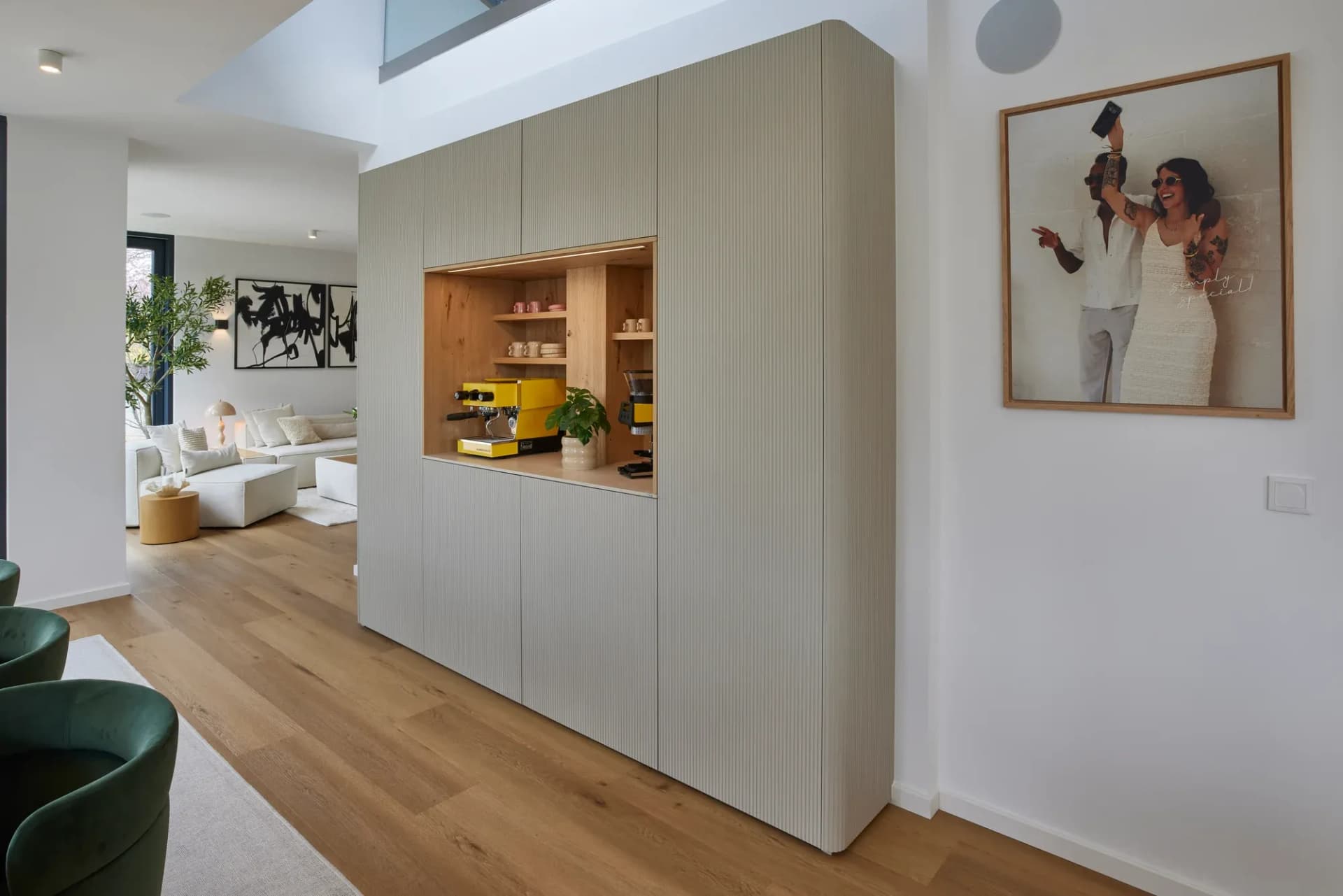 Freistehender Möbelblock mit gefrästen Rillenfronten und offener Eichennische, dahinter die Lounge.