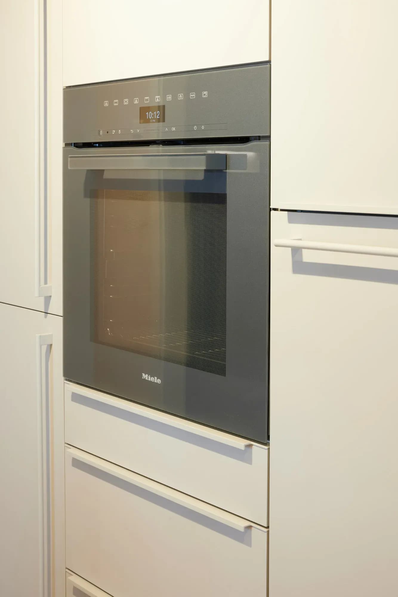 Eingebauter Miele-Backofen in der sandfarbenen Hochschrankwand.