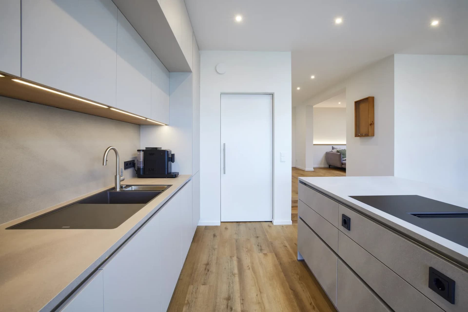 Küchenzeile mit hohen Einbaugeräten hinter schwarzem Glas und einer Arbeitsfläche in Beton-Optik.
