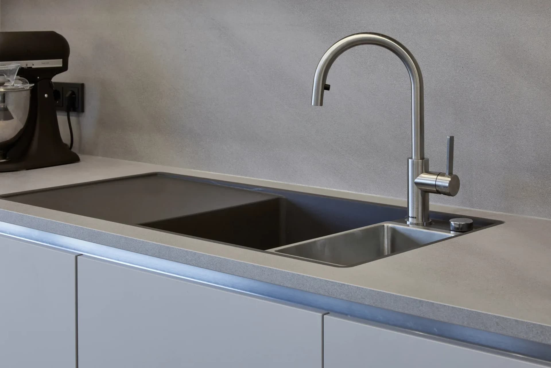 Edelstahl-Armatur und Unterbaubecken in der Arbeitsfläche in Beton-Optik.