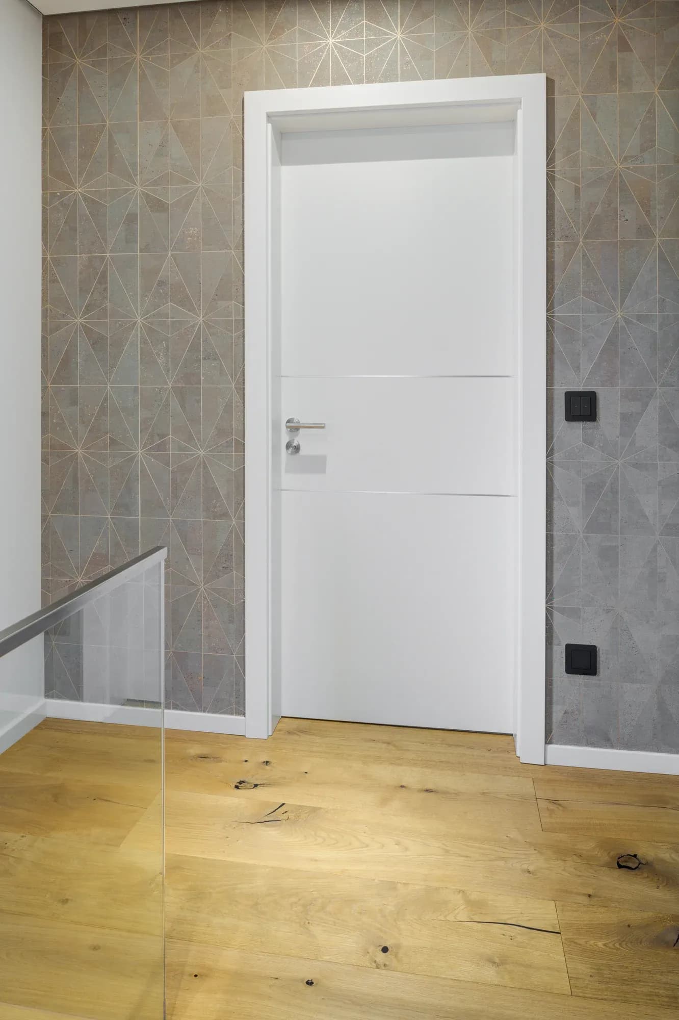 Oberes Treppenpodest mit Eiche-Landhausdiele, Glasbrüstung und gemusterter Wand