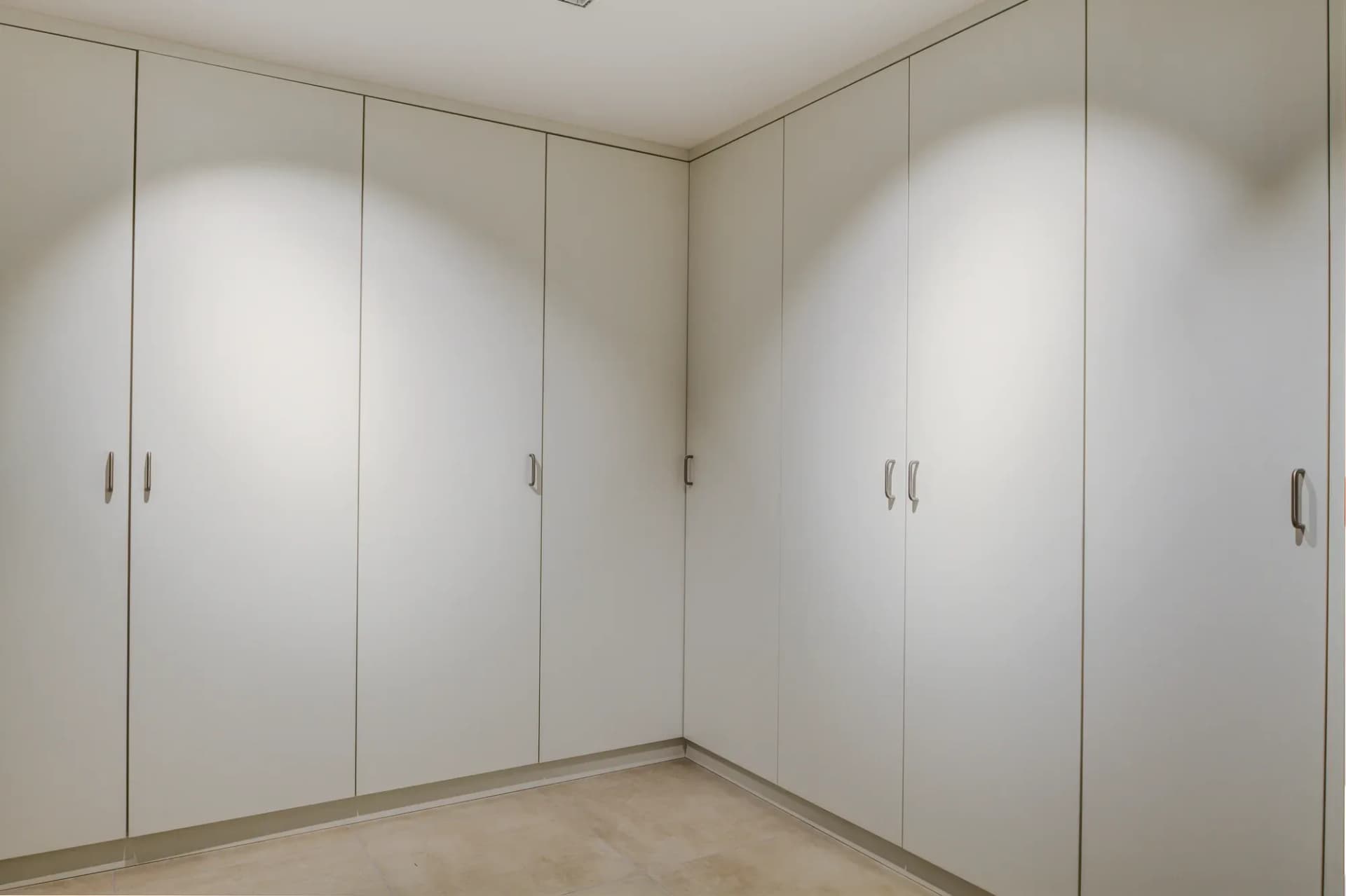 Ankleidezimmer mit raumhohen, grifflosen weißen Schrankfronten
