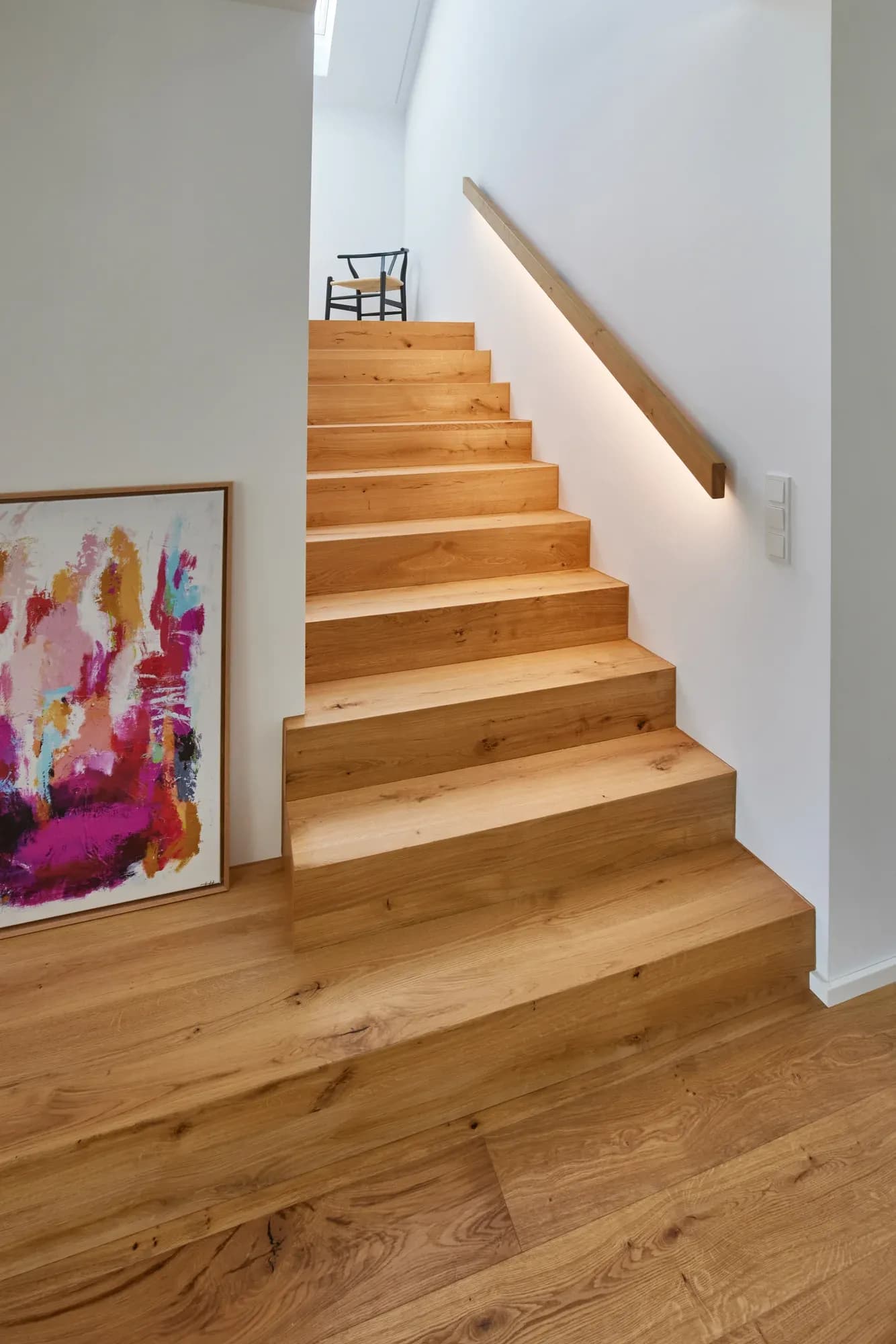 Hauswirtschaftsraum mit weißen Einbauschränken, Edelstahlspüle, Waschmaschine und Trockner sowie sichtbarer Haustechnik an der Wand.