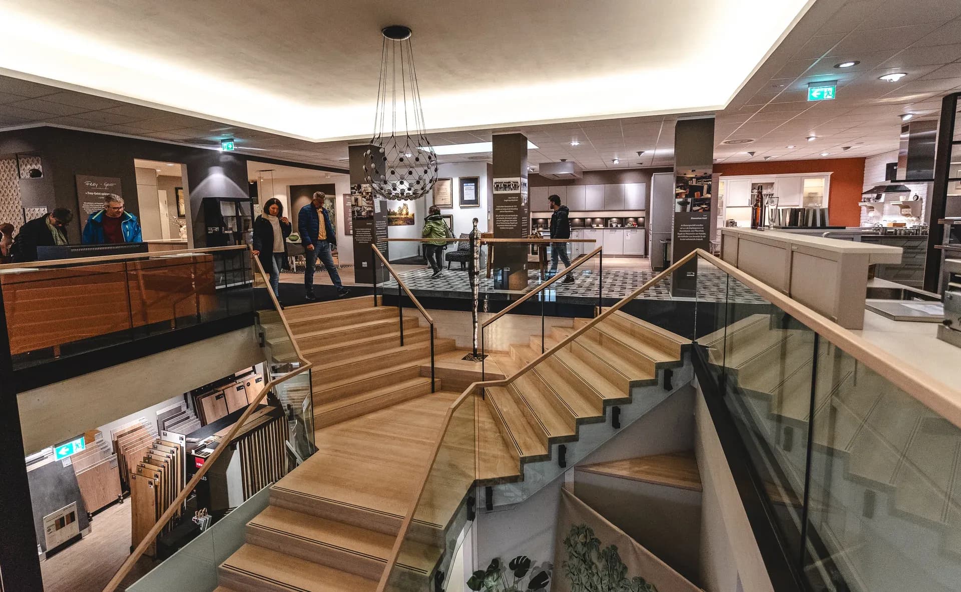 Blick in die Frey-Ausstellung in Kandel: Holztreppe zwischen den Etagen, Besucher zwischen den Küchen