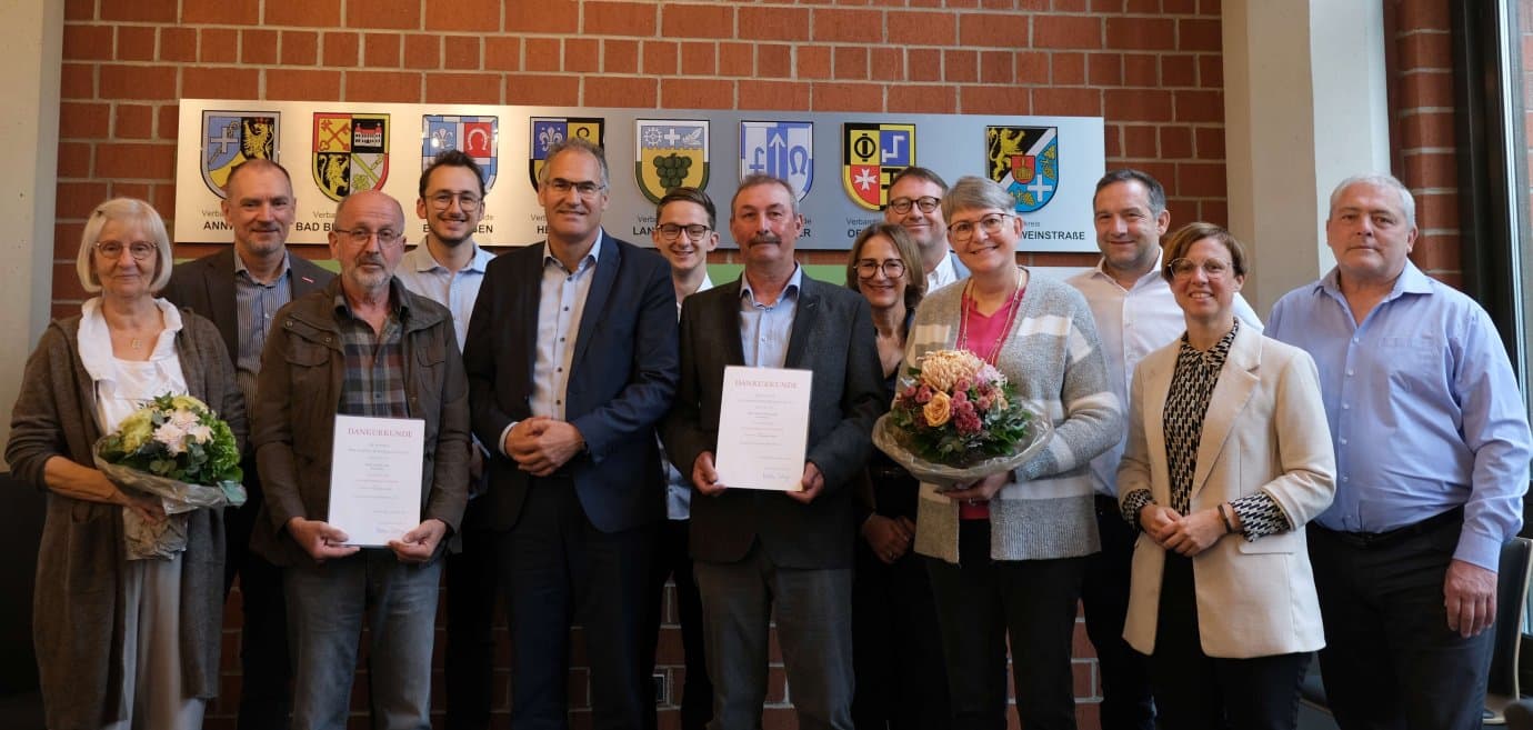 Gruppenfoto der Ehrung im Kreishaus Südliche Weinstraße: Arnold Kolb und Edwin Eichenlaub mit Dankurkunden und Blumen, umgeben von Ehrengästen