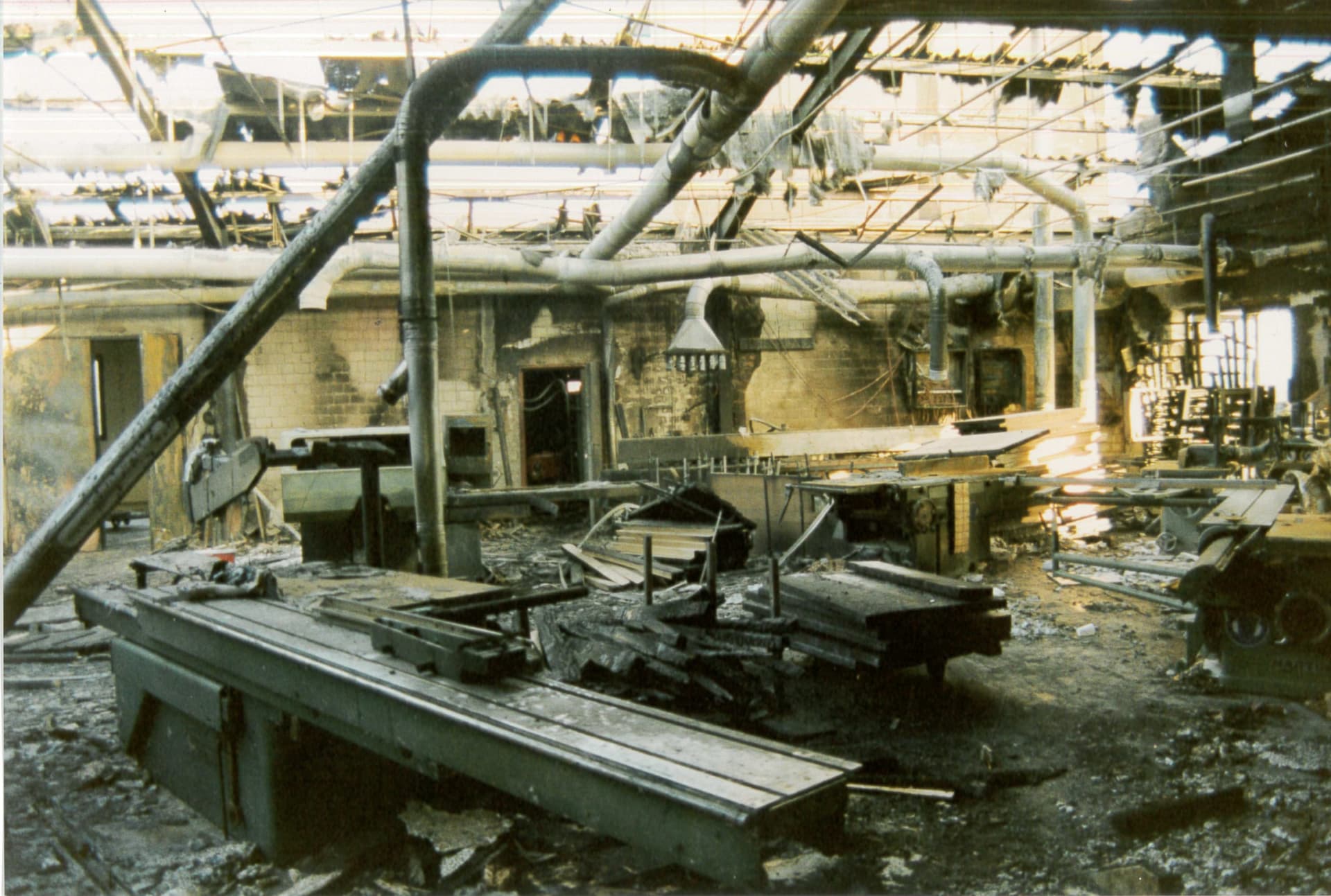 Die ausgebrannte Werkstatt in Schweighofen im Mai 1993: durchgebranntes Dach mit offenem Himmel, verkohlte Maschinen und Trümmer auf den Werkbänken.