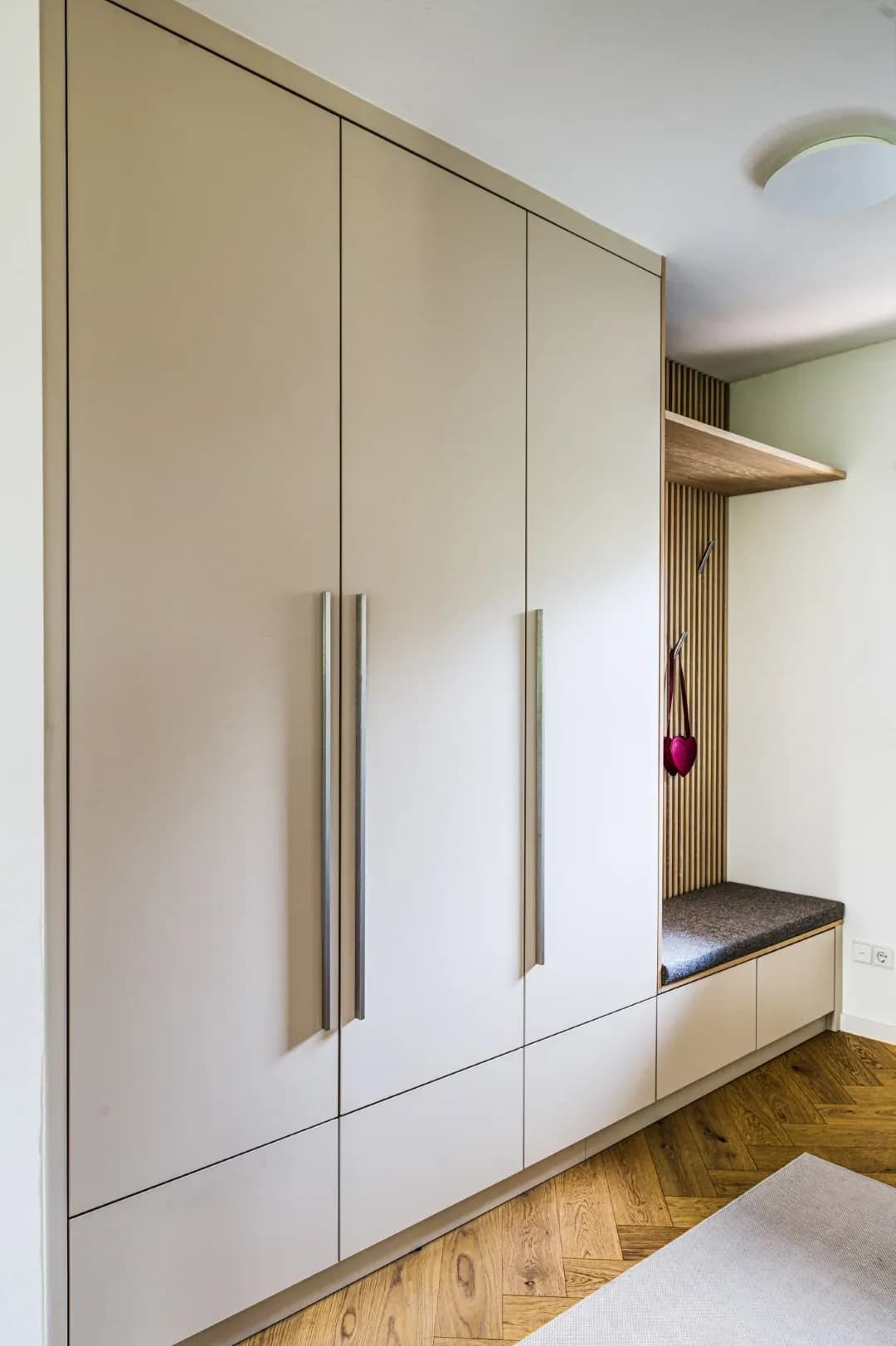 Garderobenschrank in Greige mit Sitznische, Eichen-Lamellenwand und gepolsterter Bank im Flur