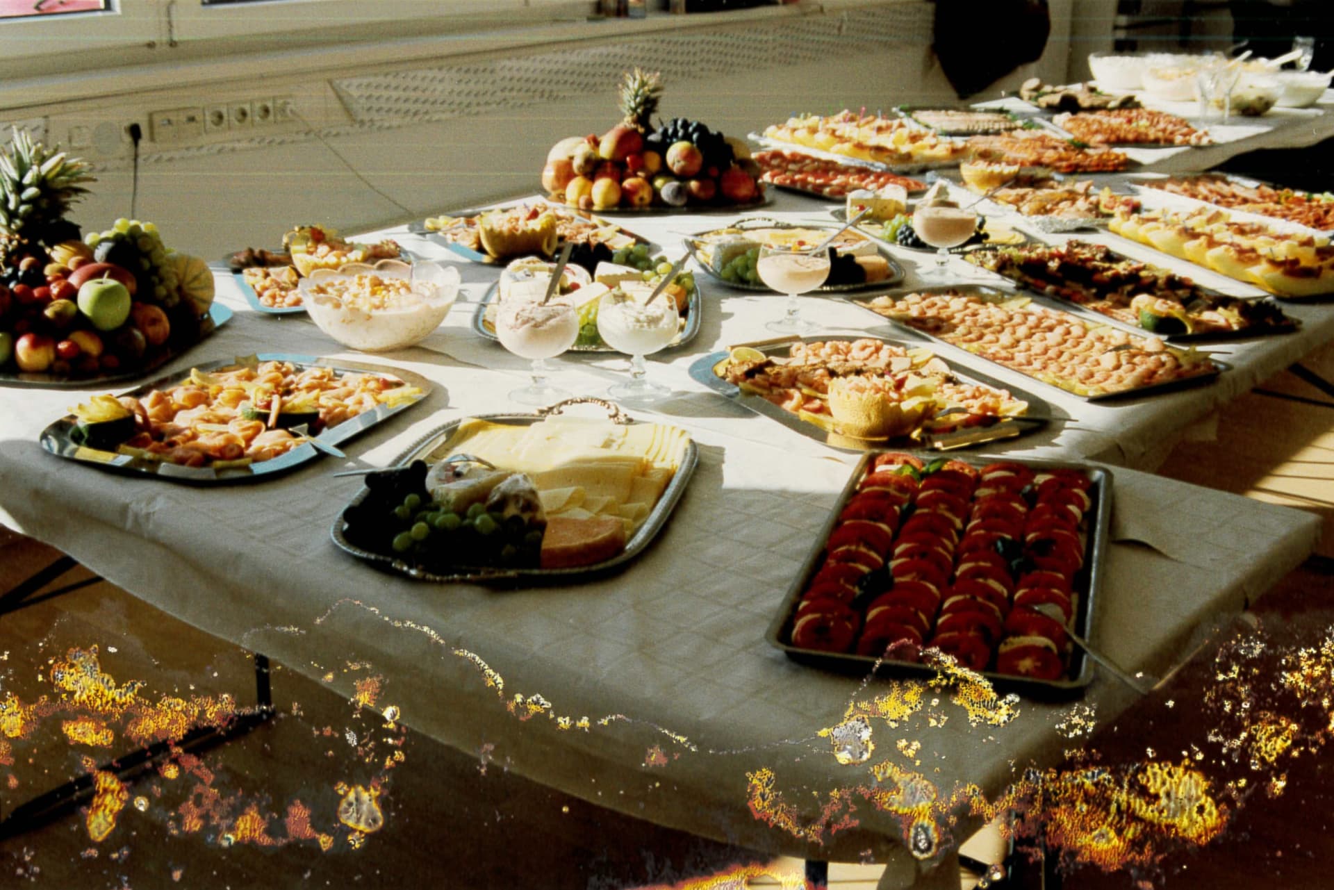 Das Eröffnungsbuffet 1994 in Kandel: lange Tafel mit Silberplatten, Lachs, Käse und zwei geschnitzten Ananas-Obstpyramiden.