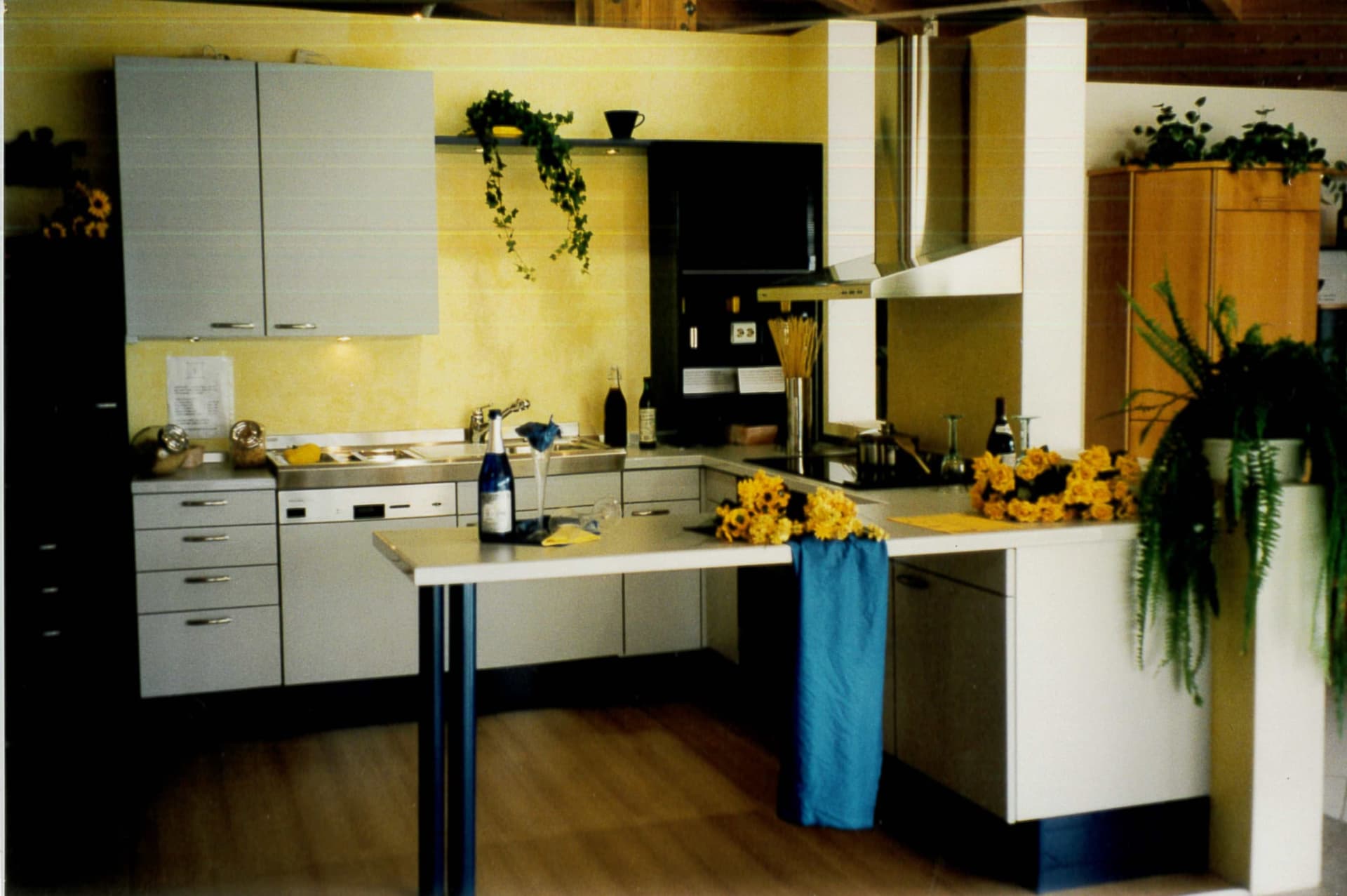 Küchenkoje der Marke Häcker in der Kandeler Ausstellung von 1994: helle Fronten, Sonnenblumen und Sektgläser zur Eröffnung.
