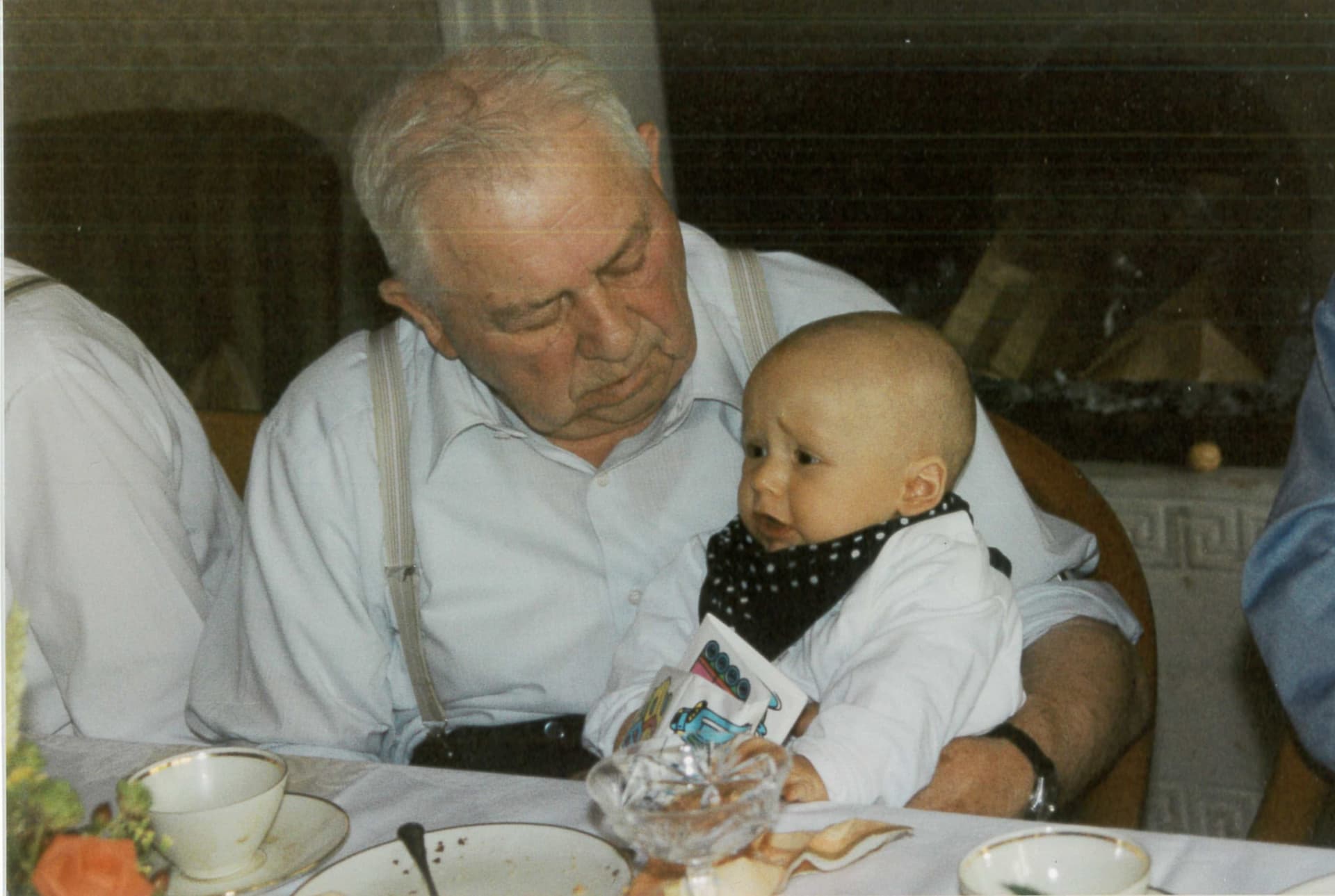 Otto Frey, weißhaarig im hellblauen Hemd mit Hosenträgern, hält seinen Urenkel Henrik als Säugling auf dem Arm — erste und vierte Generation auf einem Bild.