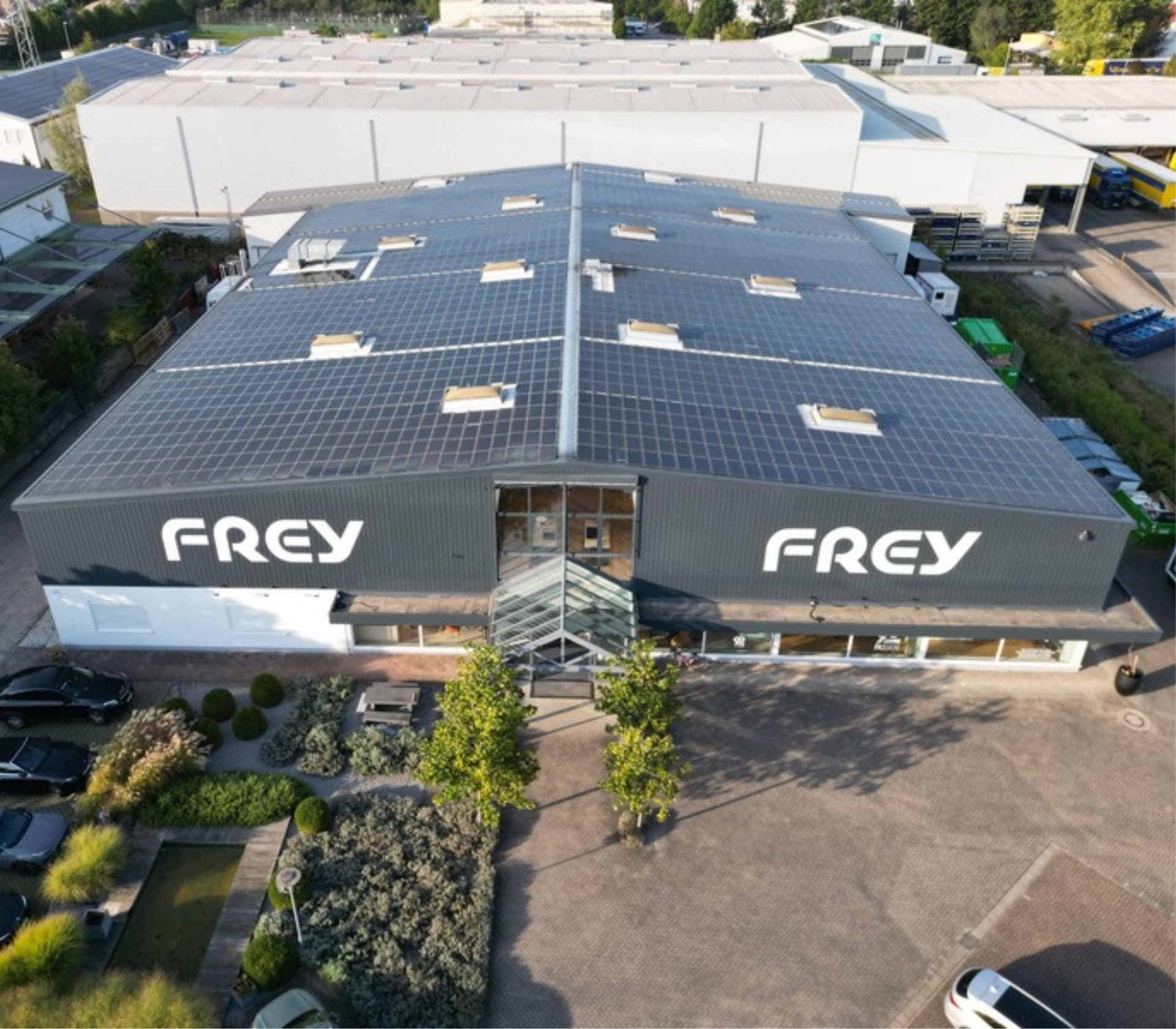 Luftaufnahme des Ausstellungsgebäudes in Kandel: die gesamte Dachfläche ist mit Photovoltaikmodulen belegt, an der Fassade zwei Frey-Schriftzüge.