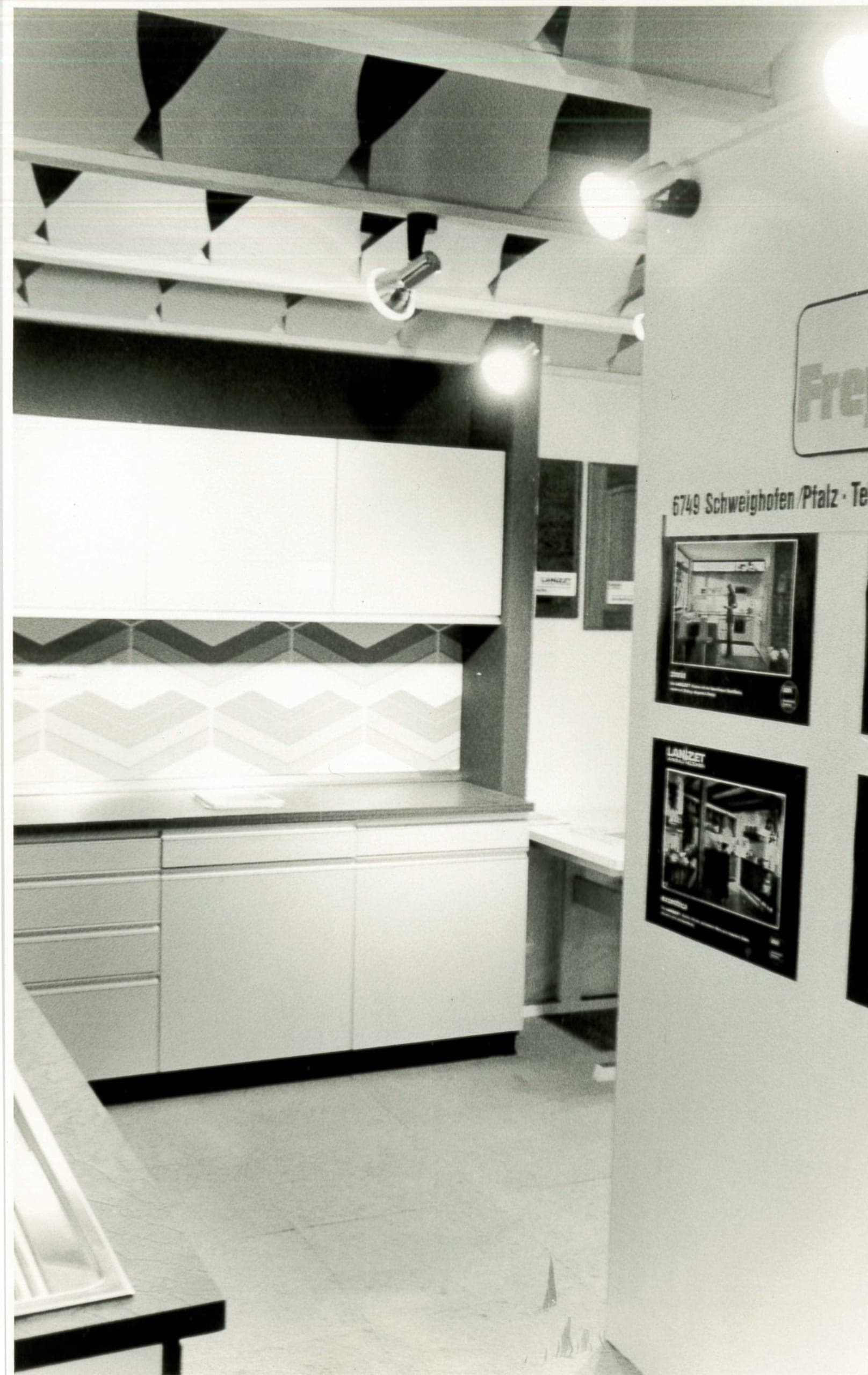 Schwarz-Weiß-Aufnahme der frühen Küchenausstellung in Schweighofen, mit einer Stellwand mit dem alten Frey-Logo und der Adresse 6749 Schweighofen/Pfalz.