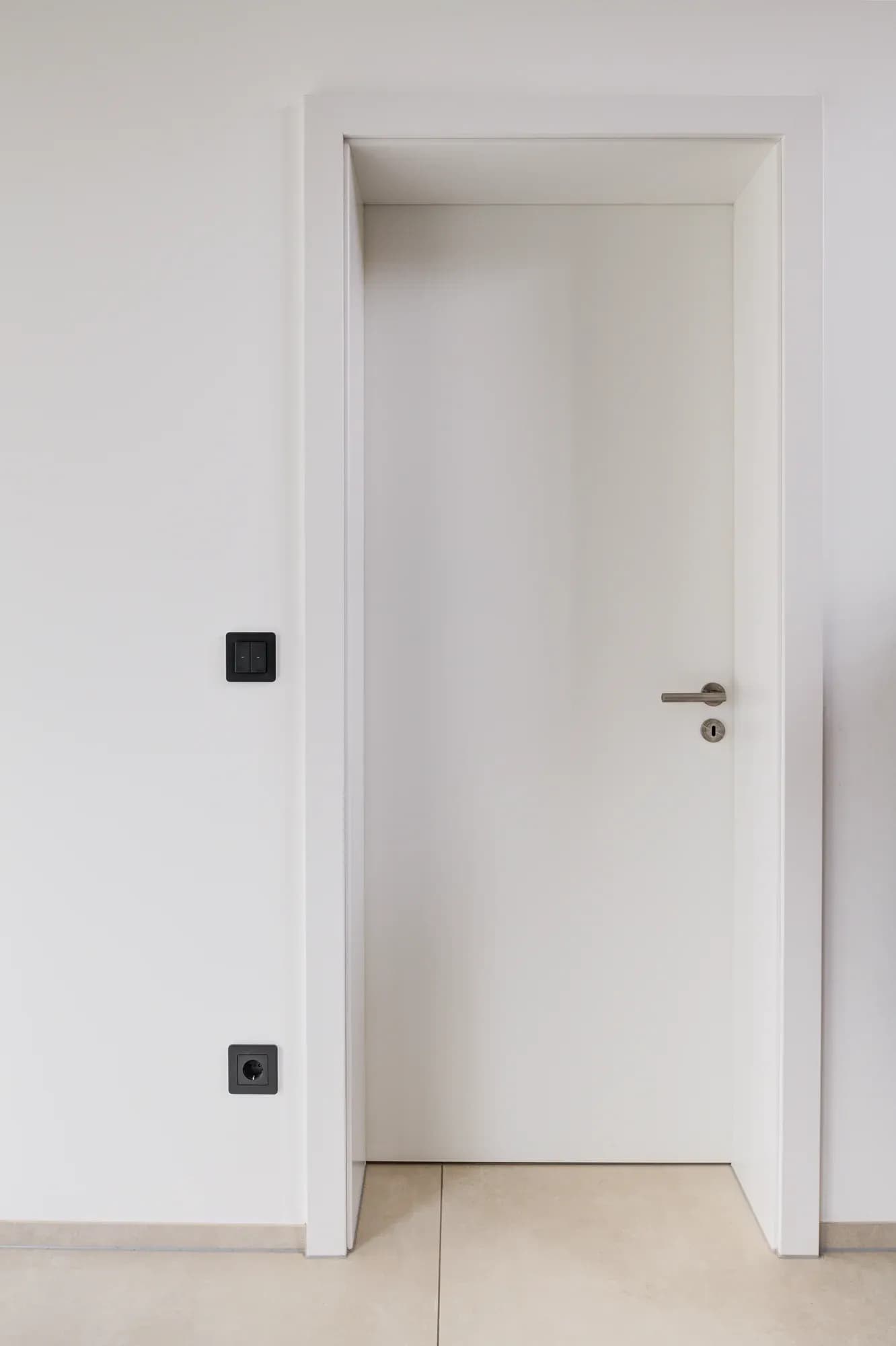 Geschlossene grifflose Innentür in Weiß mit schlankem Metallgriff, flächenbündig in glatter Wand.