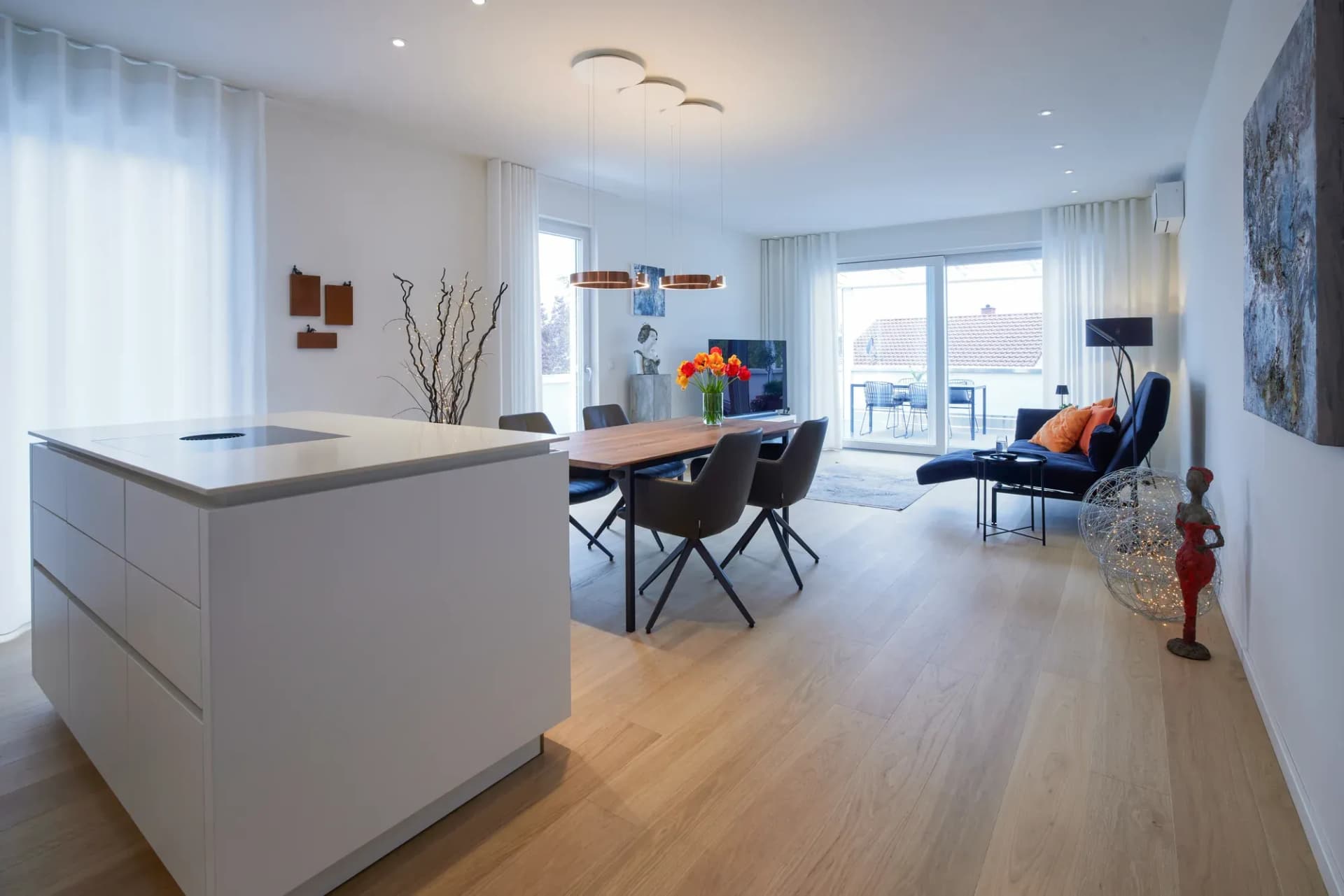 Blick über Essplatz und Wohnbereich mit durchgehender Eiche-Landhausdiele bis zur bodentiefen Fensterfront.