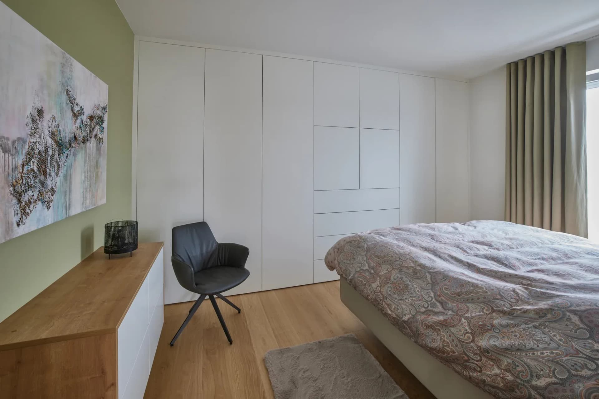 Schlafzimmer mit weißer Einbauschrankwand und freitragender Konsole aus Eiche entlang der Wand.