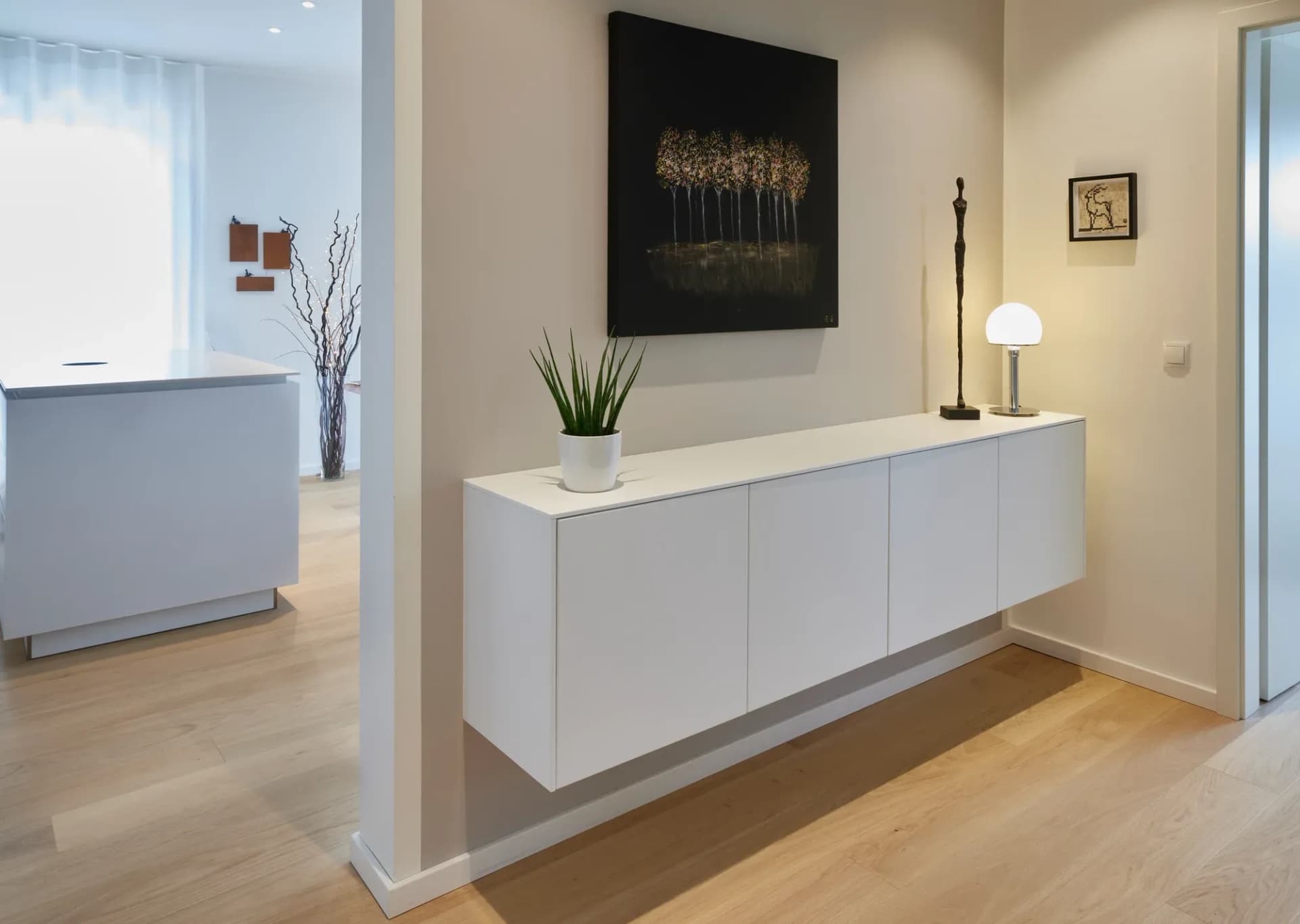 Flur mit wandhängendem weißem Sideboard, Kunst an der Wand und Eichenboden.